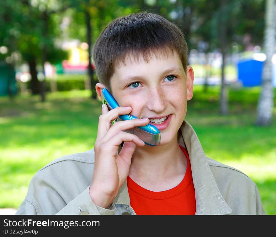 Young boy speaks by phone outdoors. Young boy speaks by phone outdoors