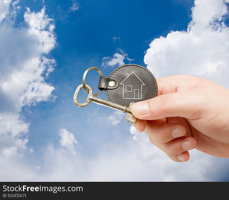 Keychain in human hand on sky background