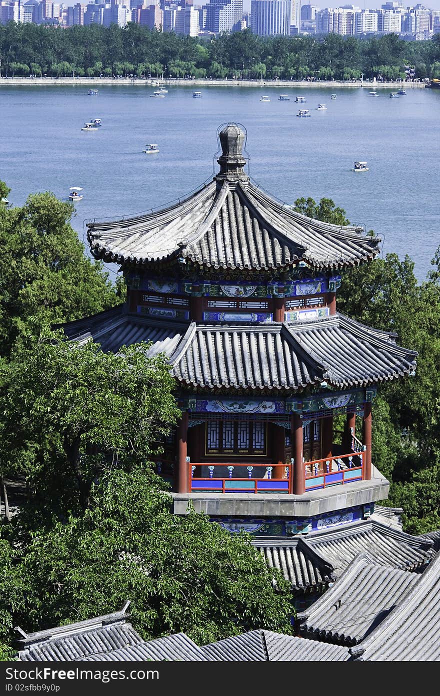 A traditional Chinese pavilion by Kunming Lake in Summer Palace, with modern buildings in the distance. A traditional Chinese pavilion by Kunming Lake in Summer Palace, with modern buildings in the distance.