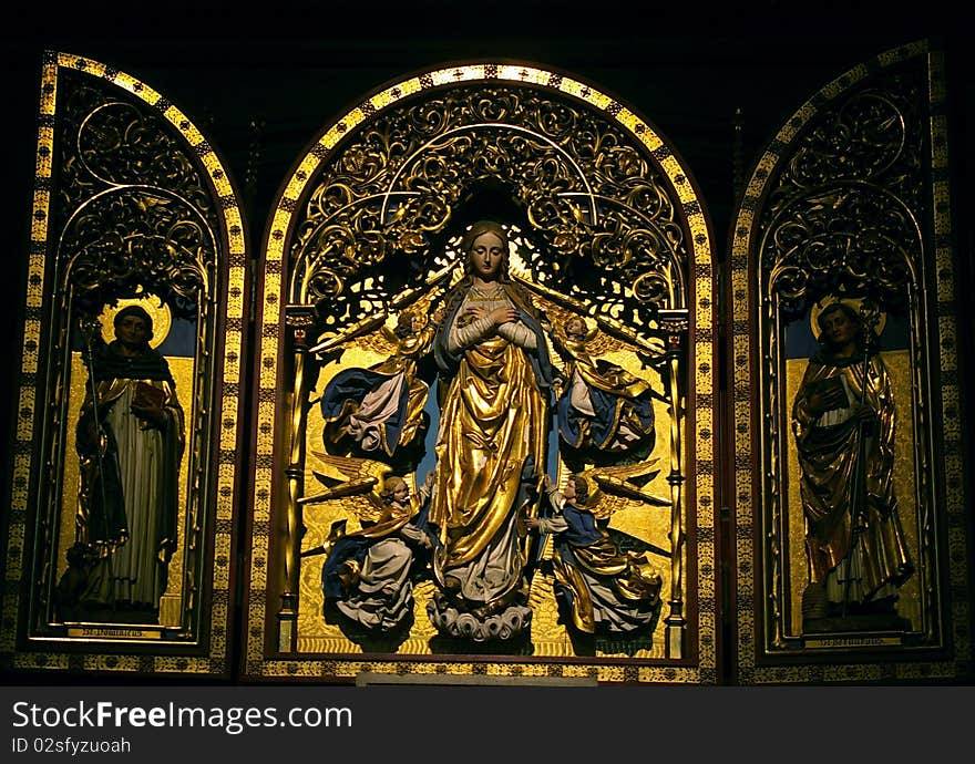 Golden medieval Triptych with Virgin flanked by archangels and saints.