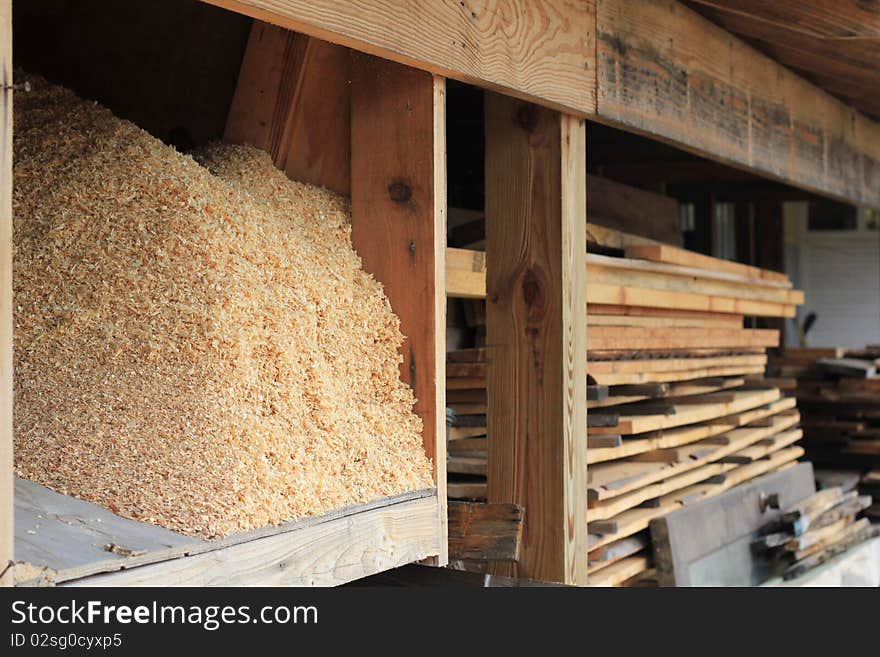 A closeup of a pile of sawdust and stacked lumber at a lumber yard. A closeup of a pile of sawdust and stacked lumber at a lumber yard.