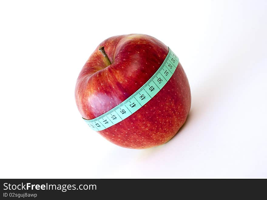 Fresh red apple wrapped up with the tape measure on the white background