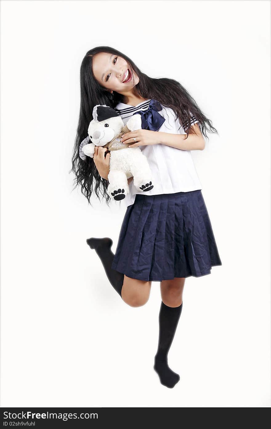 Female student in traditional uniform holding toy dog on white. Female student in traditional uniform holding toy dog on white.