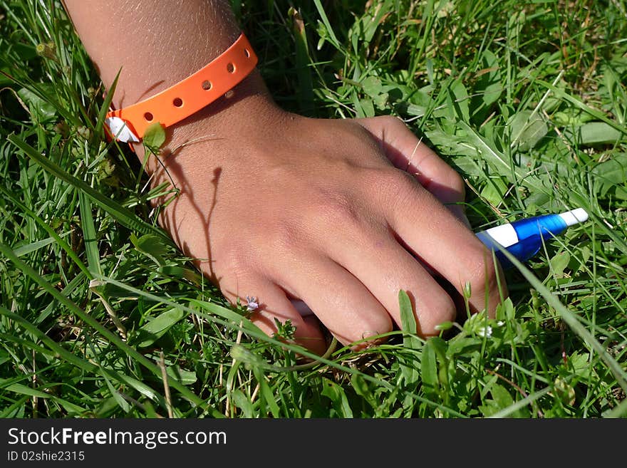 Young hand on grass with pen and platic wristband