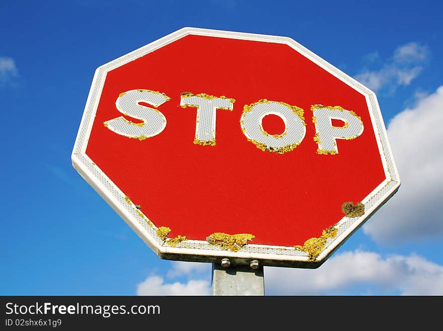 Close-up of an old red STOP sign with a blue sky background. Close-up of an old red STOP sign with a blue sky background.