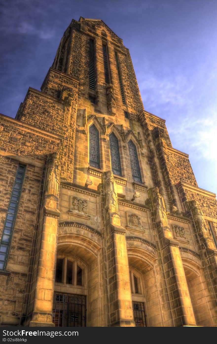 This is an HDR image of a stone church, with statues of four saints. The view is only of the front, high rising steeple, taken during the evening sunset which gives it the stone a warm glow. This is an HDR image of a stone church, with statues of four saints. The view is only of the front, high rising steeple, taken during the evening sunset which gives it the stone a warm glow.