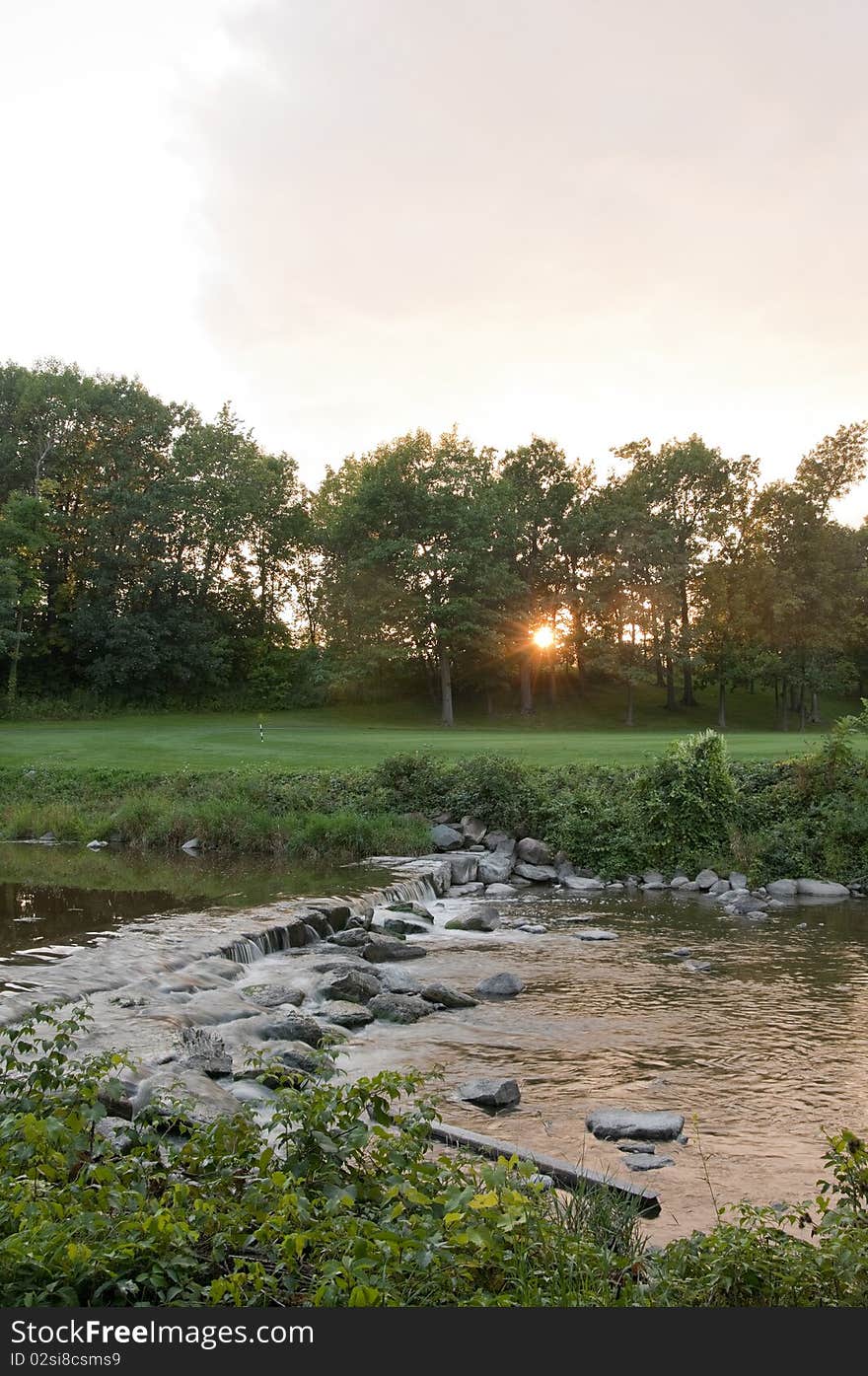 Sunset on the golf course with small river in the foreground