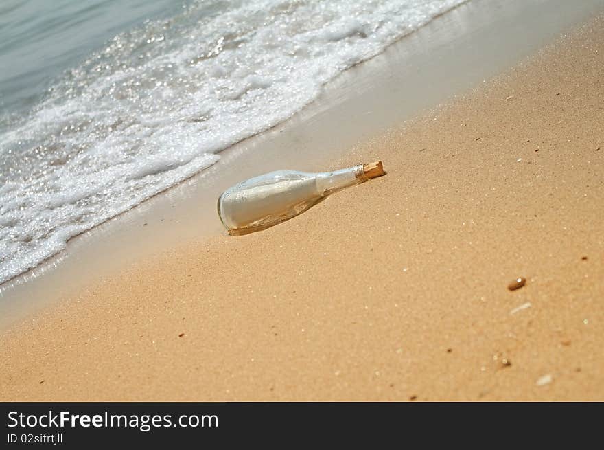 Letter in a bottle on beach with waves.