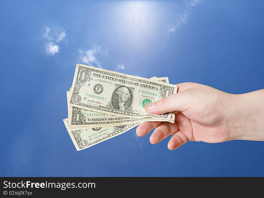 American dollar in hand on blue sky background