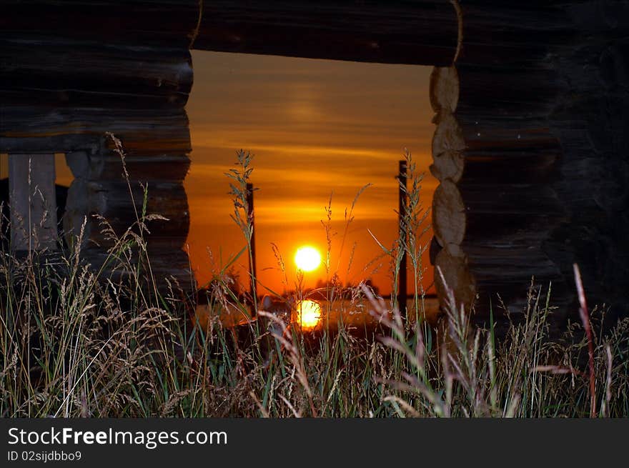 The coming sun shines through ruins of the wooden house. The coming sun shines through ruins of the wooden house.