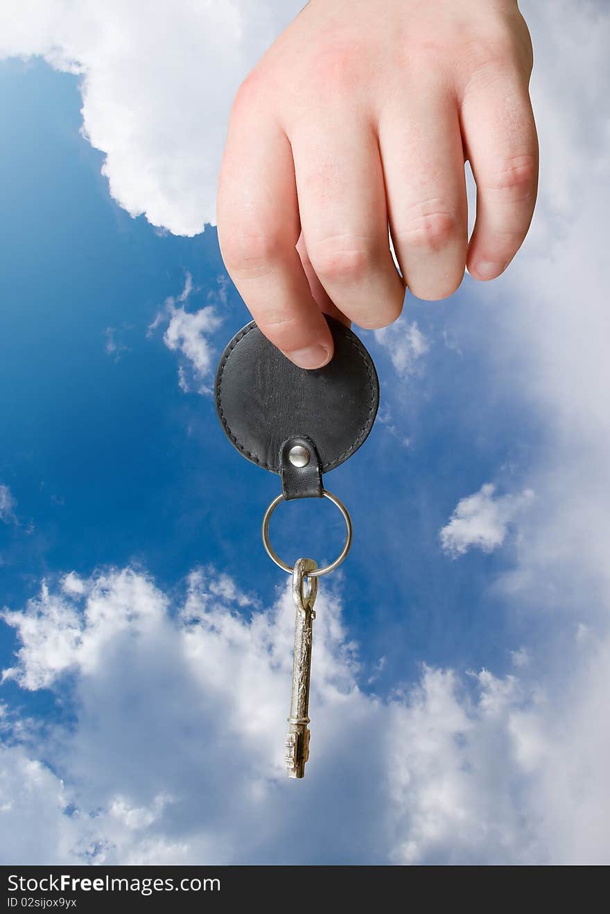 Retro key in hand on blue sky background