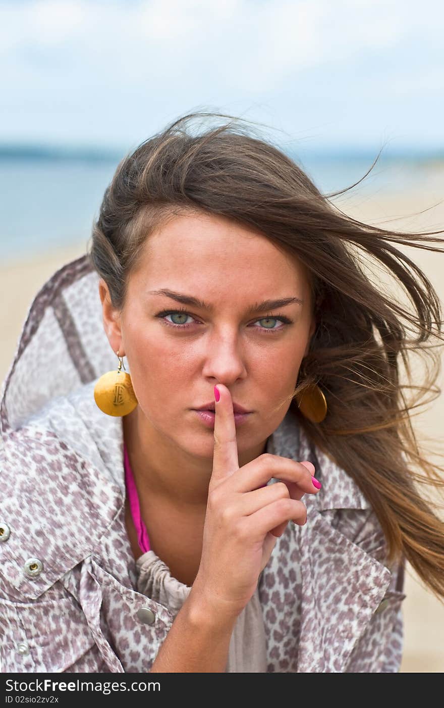 Young attractive woman with his finger around his lips. Portrait of a Woman. Outdoor, summer.