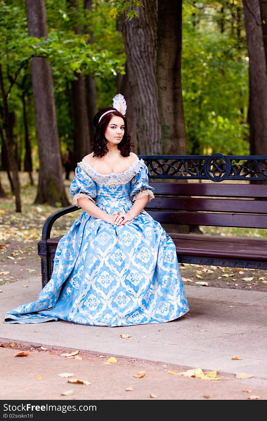 A portrait of lady in a blue baroque dress sitting on bench. A portrait of lady in a blue baroque dress sitting on bench