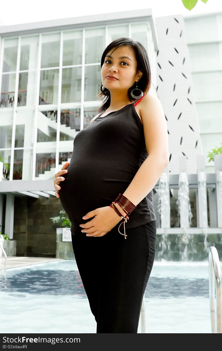 Portrait of healthy Asian ethnic pregnant woman standing by the pool. Portrait of healthy Asian ethnic pregnant woman standing by the pool