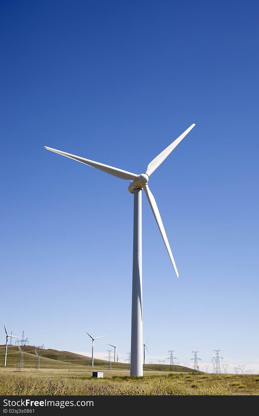 The white wind turbine generating electricity on blue sky. The white wind turbine generating electricity on blue sky