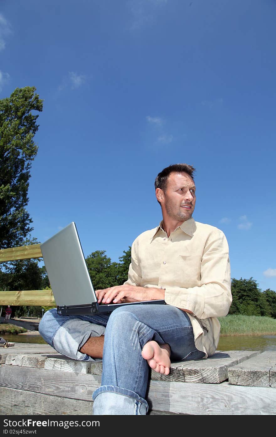 Man using laptop computer on a pontoon. Man using laptop computer on a pontoon