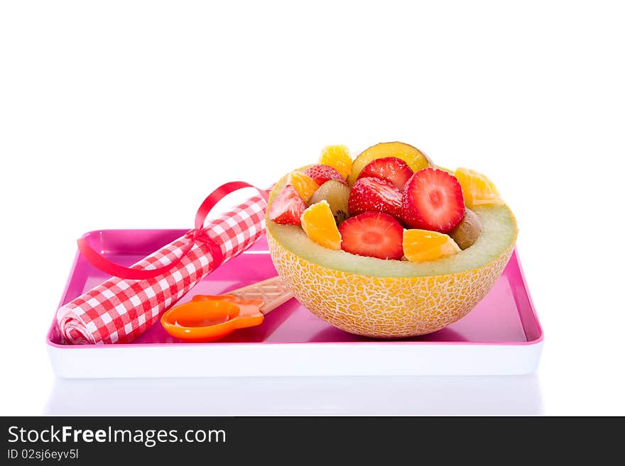 A melon filled with juicy colorful fruits on a pink plate isolated over white. A melon filled with juicy colorful fruits on a pink plate isolated over white