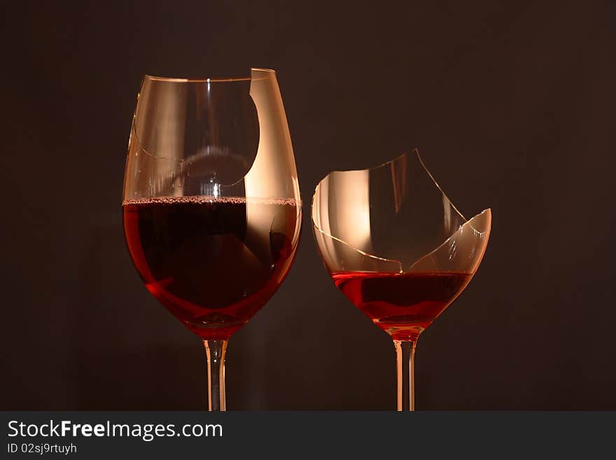 Two broken goblets with red wine on dark background. Two broken goblets with red wine on dark background