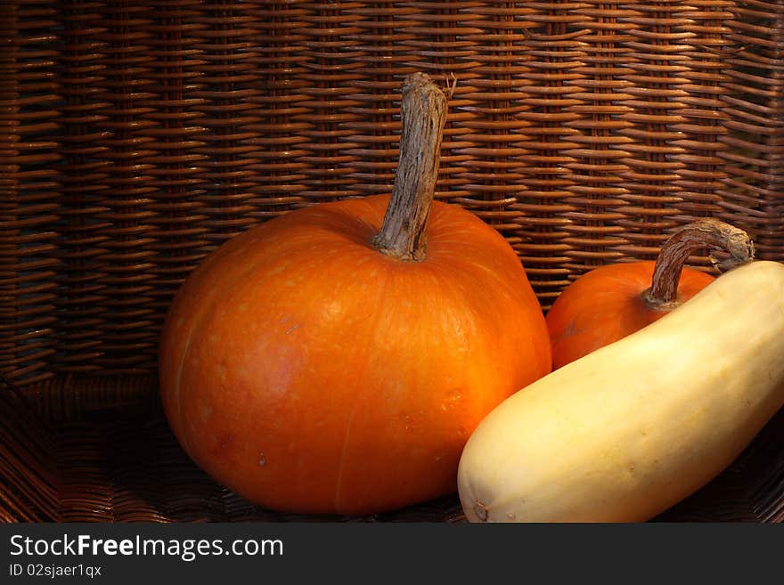 Two pumpkins and marrow squash inside wicker basket. Two pumpkins and marrow squash inside wicker basket