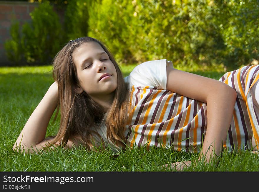 Pretty young teenage girl resting on the bed of grass and enjoying beautiful day. Pretty young teenage girl resting on the bed of grass and enjoying beautiful day.