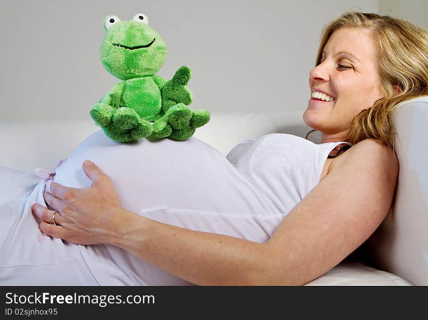 Young fresh pregnant woman with baby toys. Isolated over white background. Young fresh pregnant woman with baby toys. Isolated over white background.