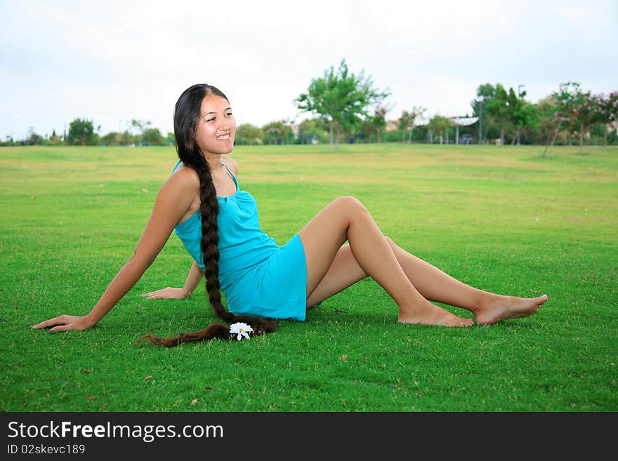 Young woman with long hair sitting on green grass in the park. Young woman with long hair sitting on green grass in the park