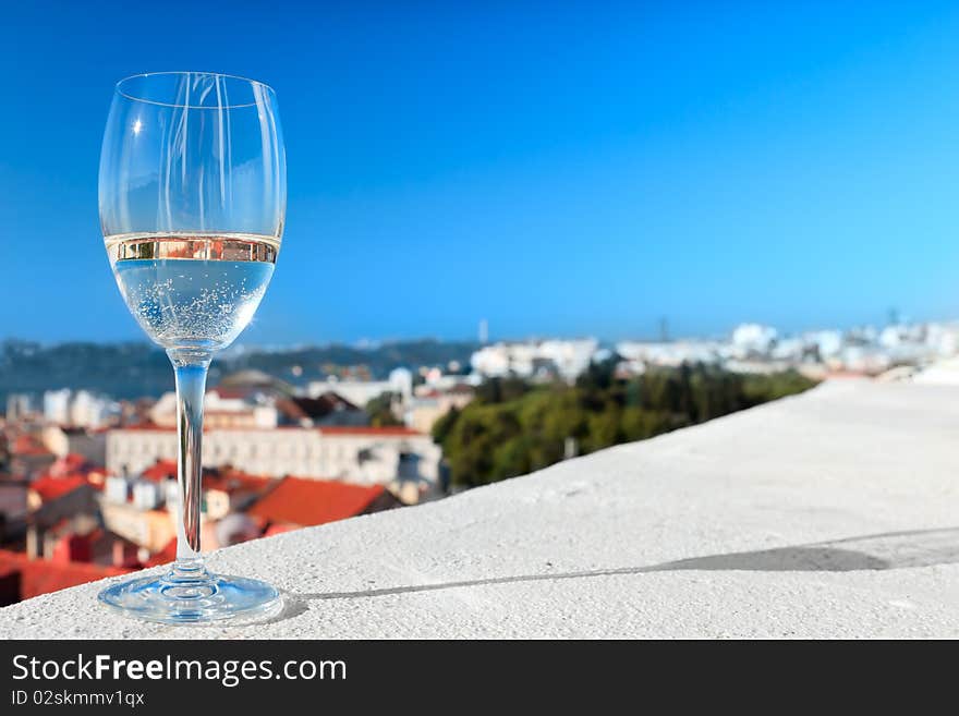 Glass Of White Wine Against The Roofs And Blue Sky