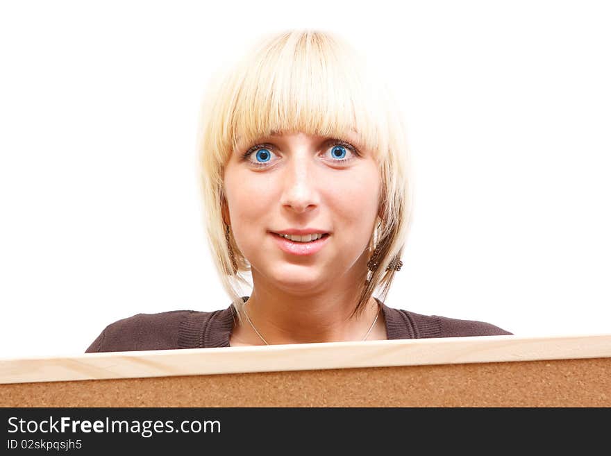 An attractive young woman with blue eyes looking surprised behind a corkboard. An attractive young woman with blue eyes looking surprised behind a corkboard