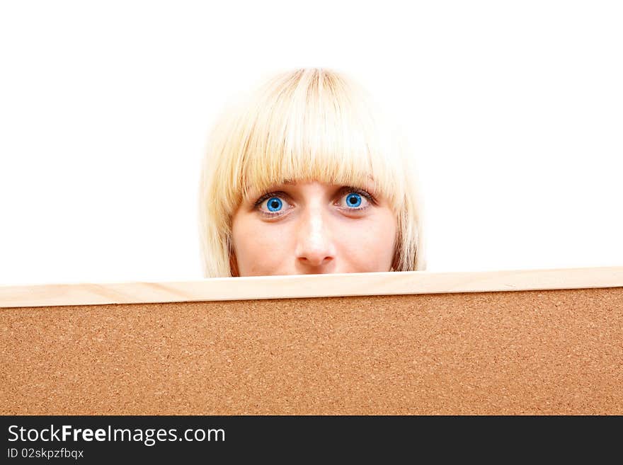 An attractive young girl with blue eyes looking out behind a corkboard. An attractive young girl with blue eyes looking out behind a corkboard