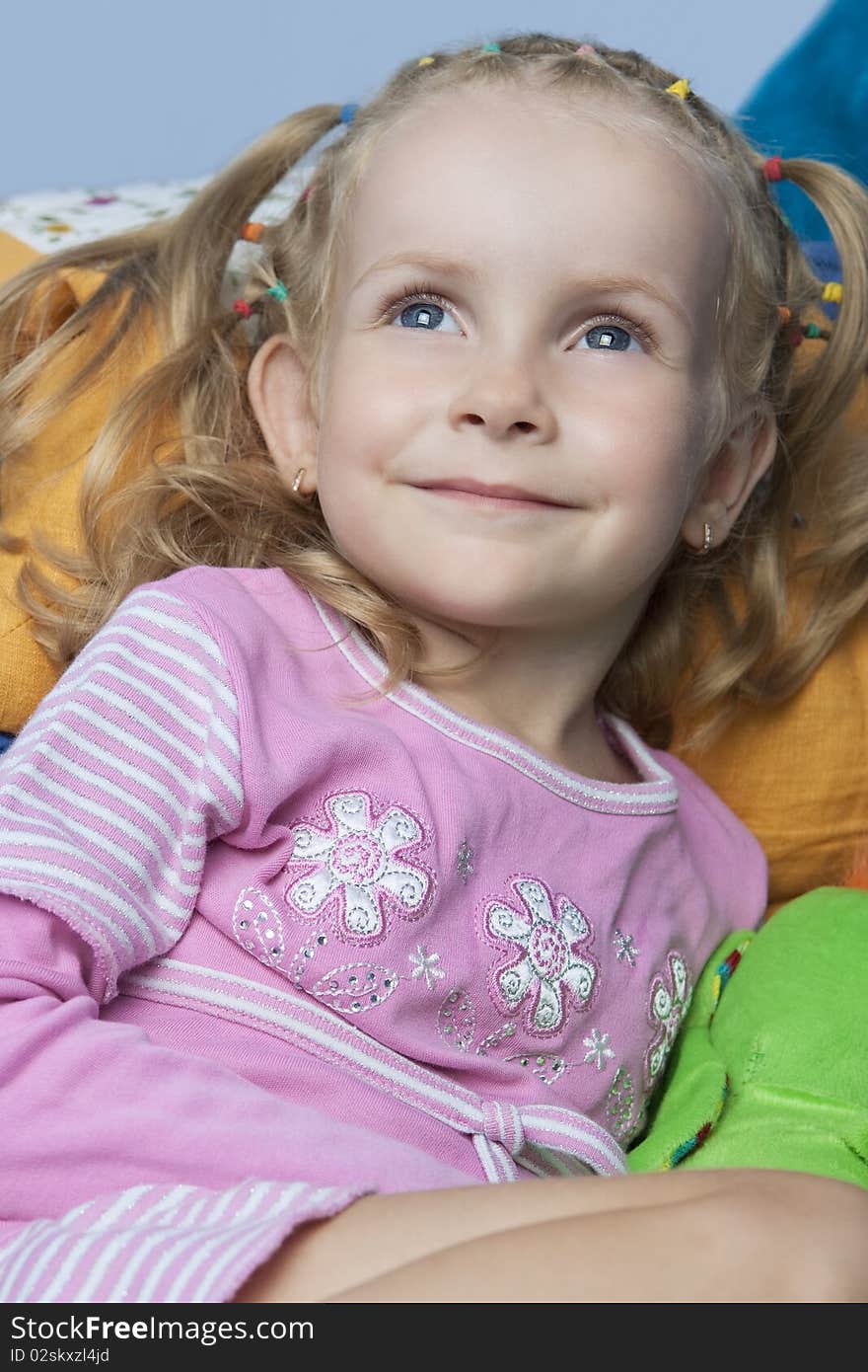 Pretty caucasian young blond little girl with happy smile on face sitting with pleasure and looking up with positive expression. Pretty caucasian young blond little girl with happy smile on face sitting with pleasure and looking up with positive expression