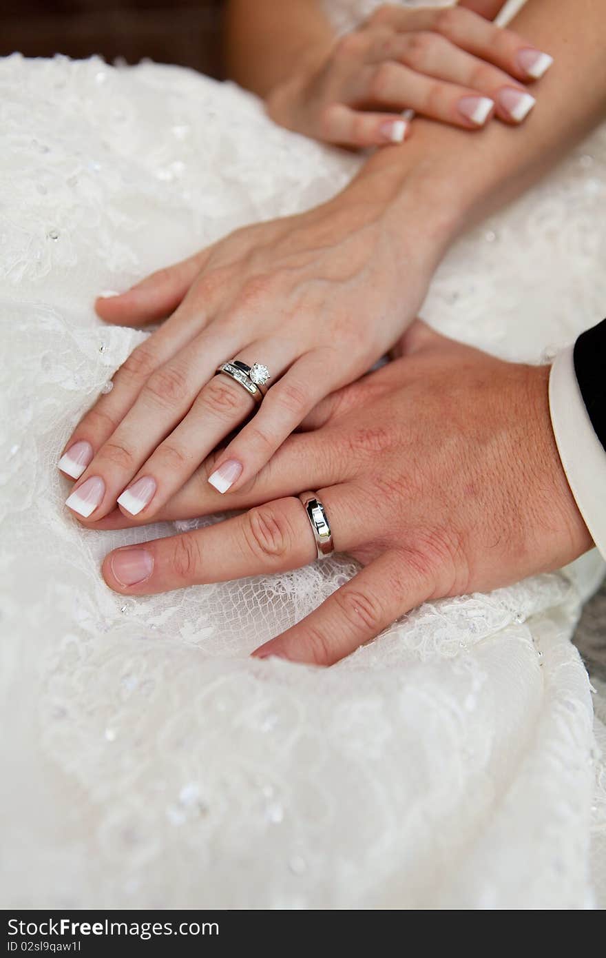 Gently connected hands of a newly-married couple with wedding rings