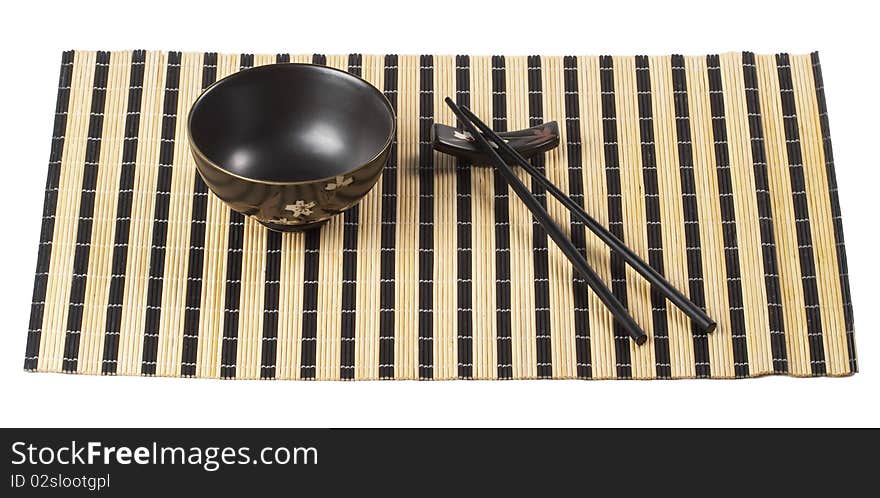 Wooden chopsticks and little ceramic bowl on the bamboo mat isolated over white background. Wooden chopsticks and little ceramic bowl on the bamboo mat isolated over white background