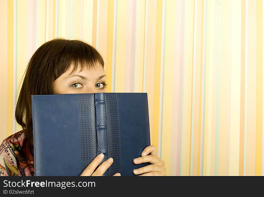 Young beautiful girl in the room face covered notebooks. Young beautiful girl in the room face covered notebooks