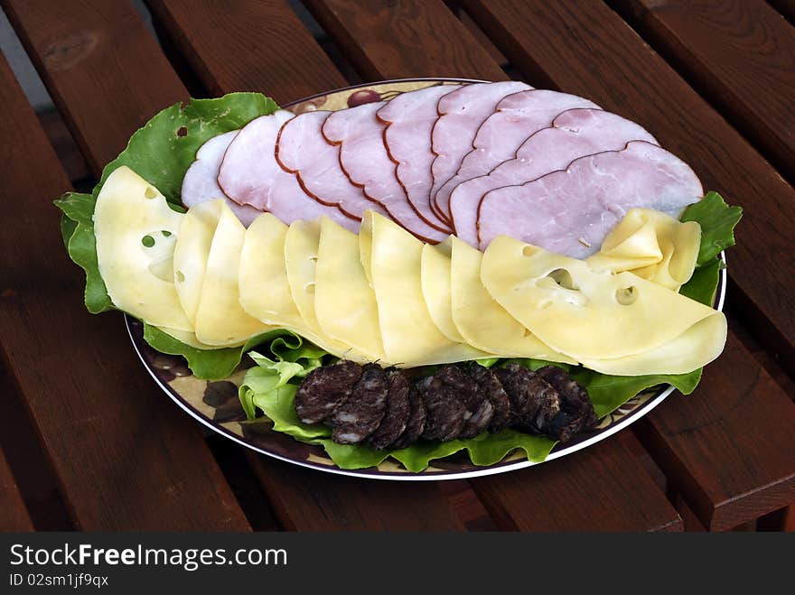 A plate of cheese and ham on lettuce. A plate of cheese and ham on lettuce