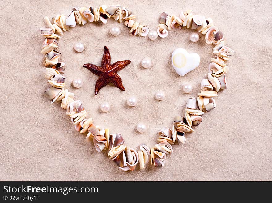 Seashells in sand in the form of heart