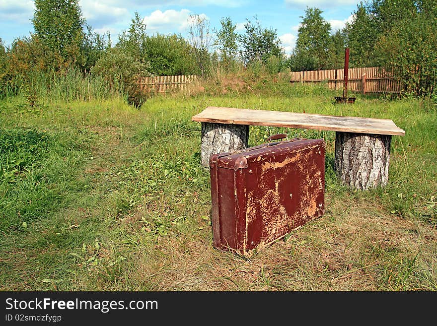 Old valise near wooden bench