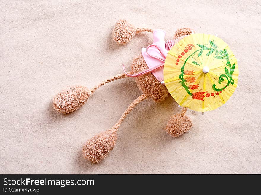 Plush toy under the beach umbrella on the sand