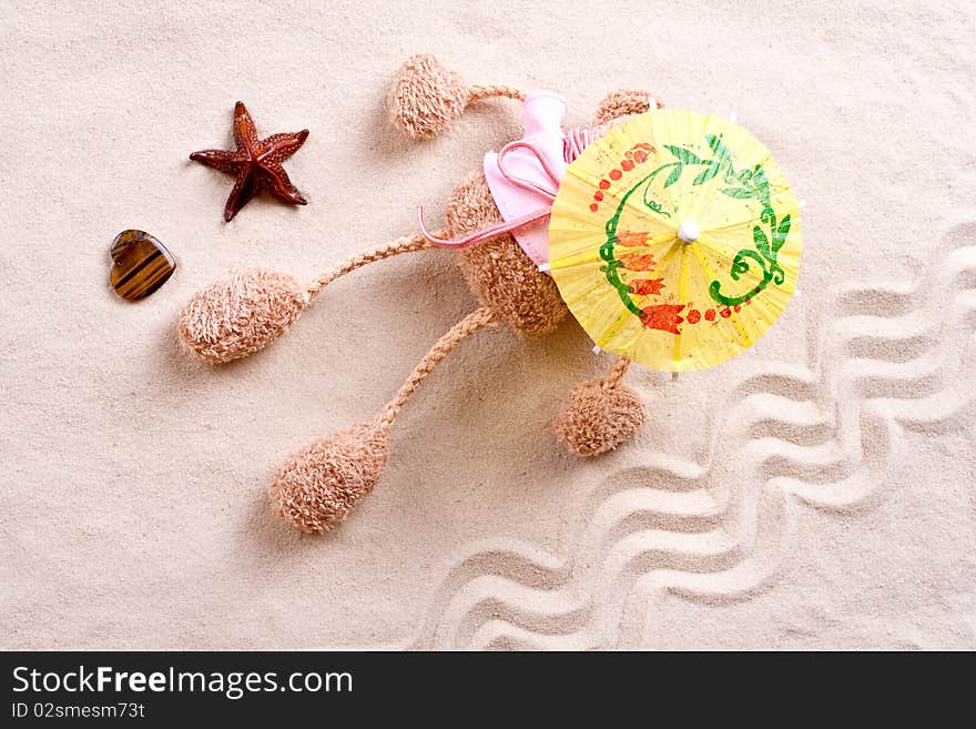 Plush toy under the beach umbrella on the sand