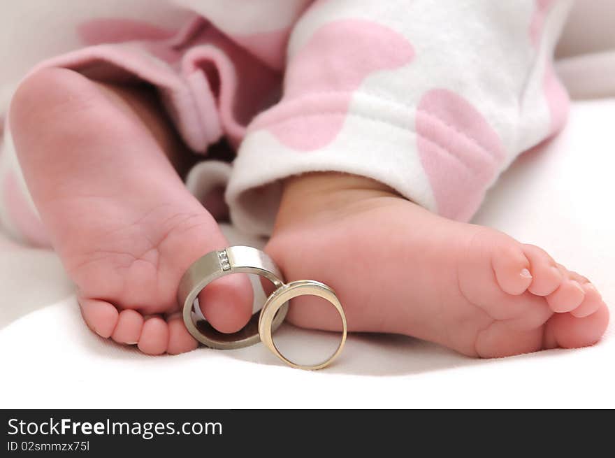 Wedding rings on the toes of a baby girl wearing white and pink clothes