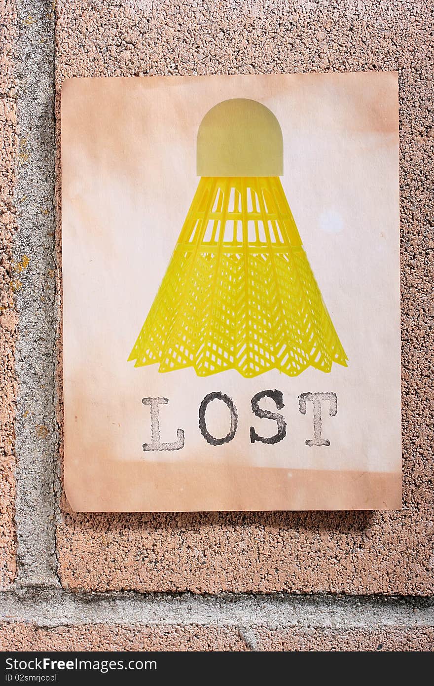 A lost sign with a yellow badminton shuttlecock hanging on a wall. A lost sign with a yellow badminton shuttlecock hanging on a wall.