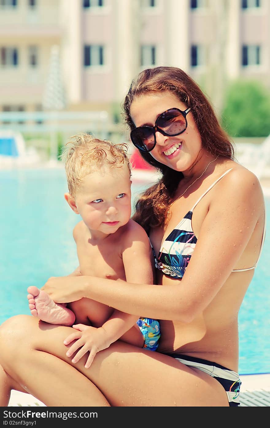 Portrait of smiling beautiful woman and her little cute sun in pool outdoor. Portrait of smiling beautiful woman and her little cute sun in pool outdoor