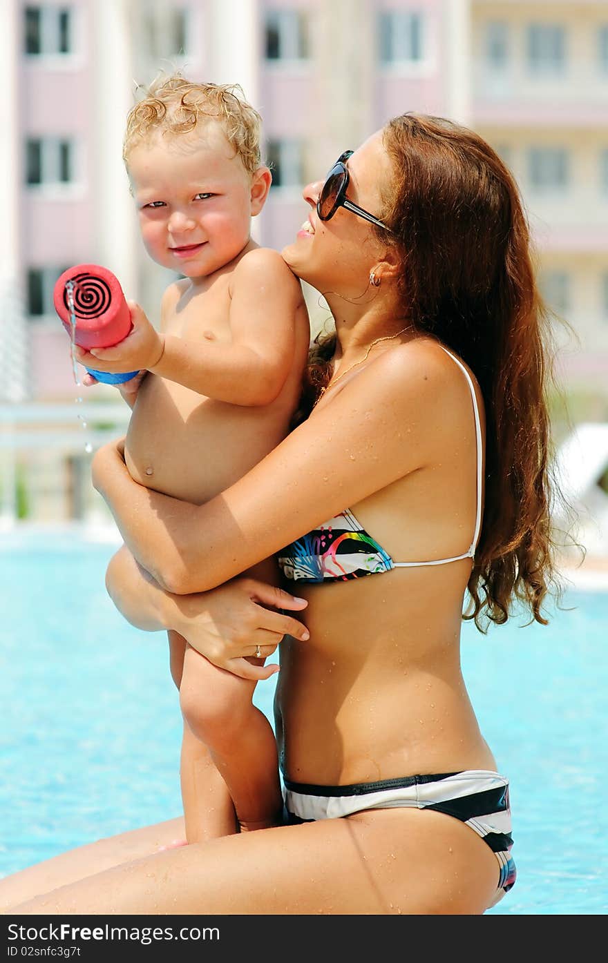 Portrait of smiling beautiful woman and her little cute sun in pool outdoor. Portrait of smiling beautiful woman and her little cute sun in pool outdoor