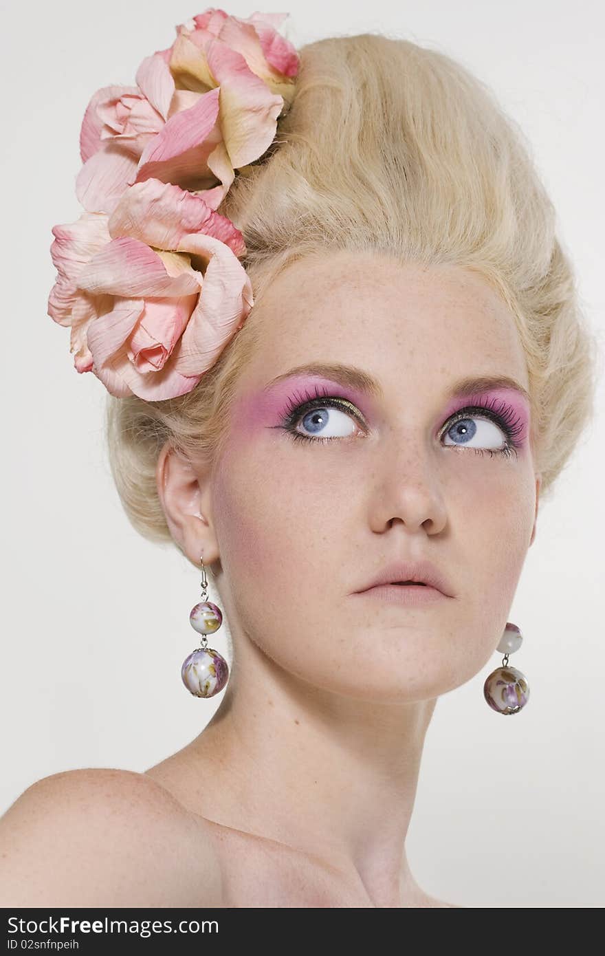 Portrait of beautiful young woman with stylish make-up and medieval hairstyle with roses