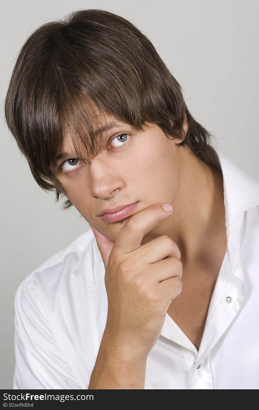 Closeup of a handsome young man thinking against white background