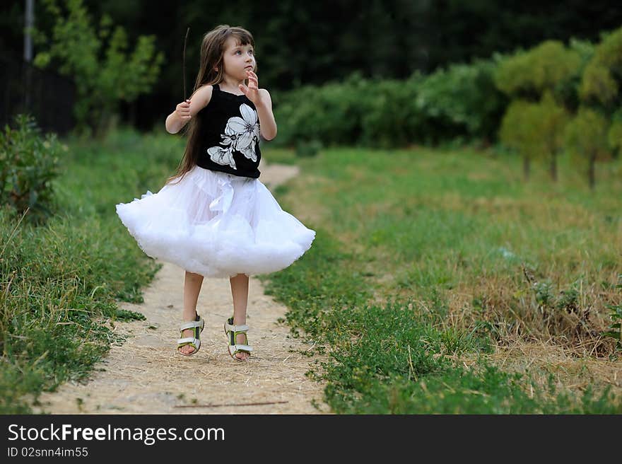 Adorable toddler girl in white tutu skirt with very long dark  fluttering hair jump  on country road. Adorable toddler girl in white tutu skirt with very long dark  fluttering hair jump  on country road