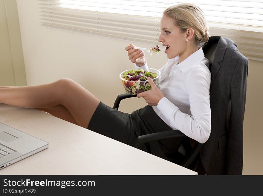 Young businesswoman eating salad in her office. Young businesswoman eating salad in her office