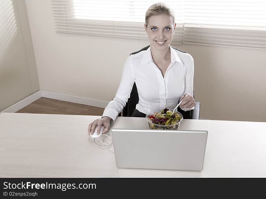 Young businesswoman eating salad in her office. Young businesswoman eating salad in her office