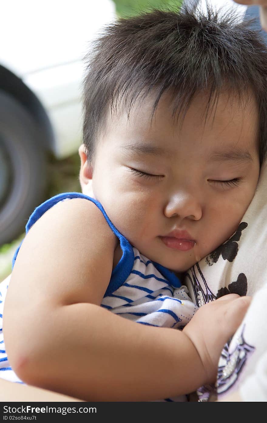 Happy baby sleeping in the arms of his mother.