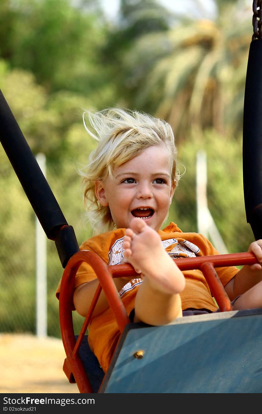 Cute little boy on a swing at the playground.