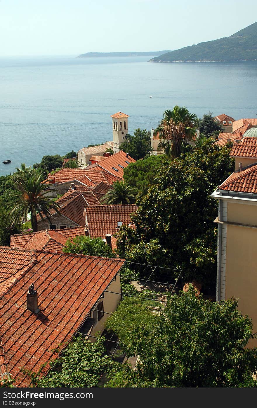 Idillic view of Mediterranean town - Hertsegnovi, Montenegro. Red roofs, blue sea, green plants - ideal summer landscape. Idillic view of Mediterranean town - Hertsegnovi, Montenegro. Red roofs, blue sea, green plants - ideal summer landscape.